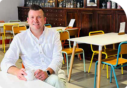 man sitting at a table in a café with a drink
